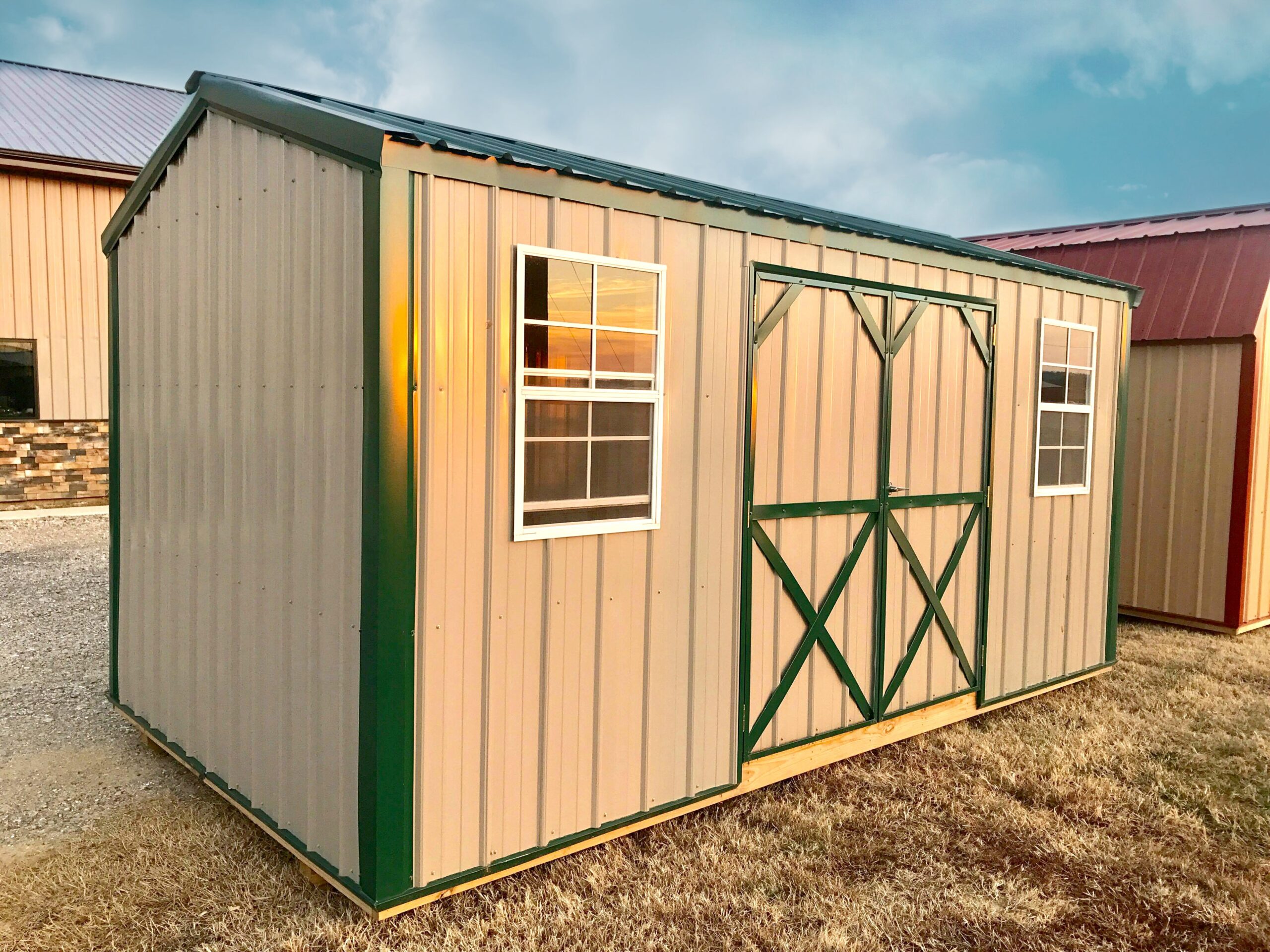 Tan all metal shed with green trim and roof