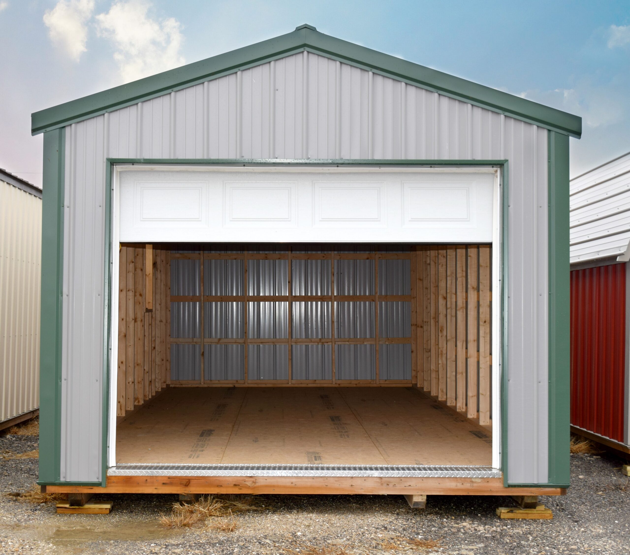 Gray metal opened garage with white door and green trim and roof