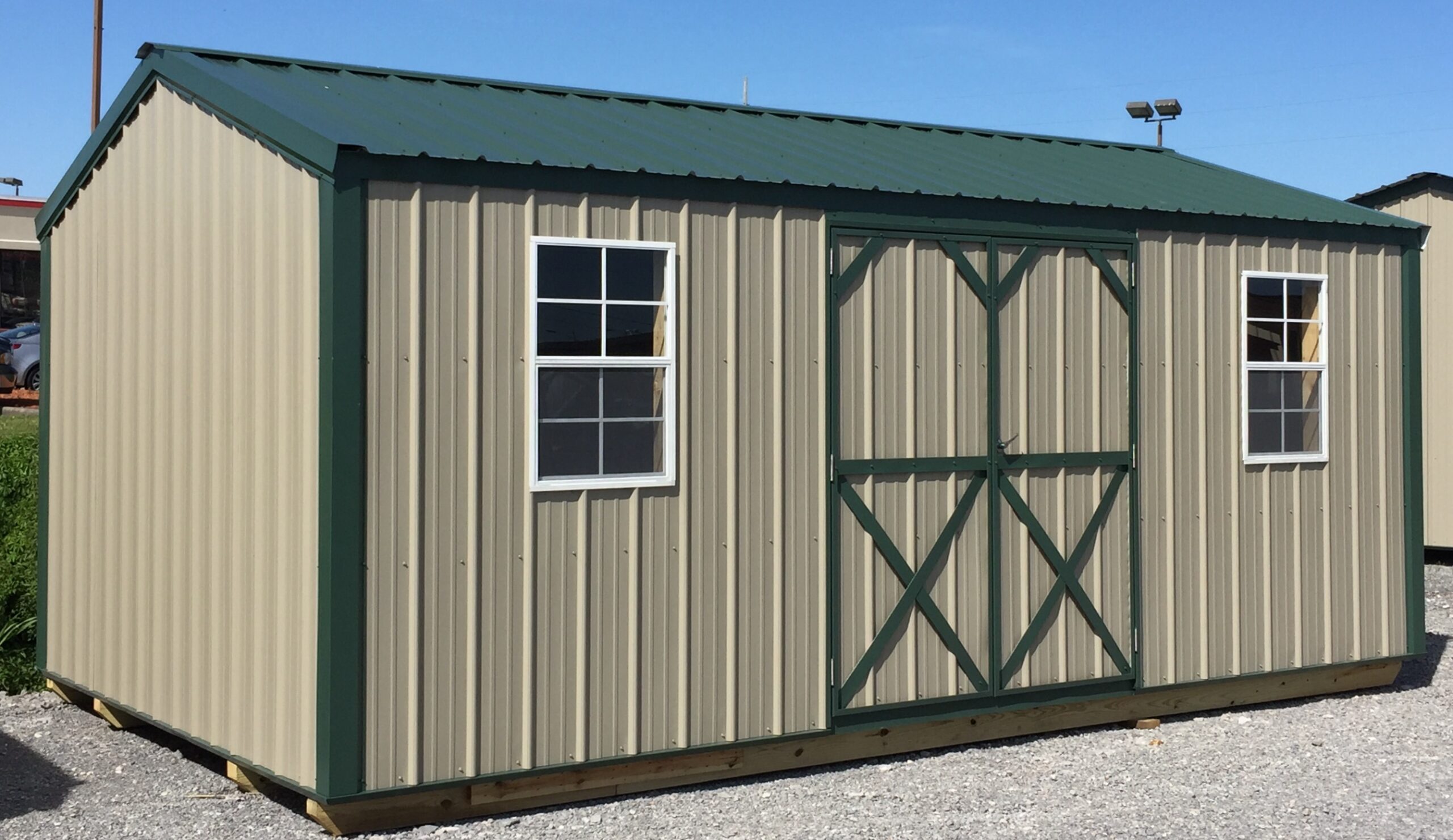 Tan metal garden shed with green trim and roof