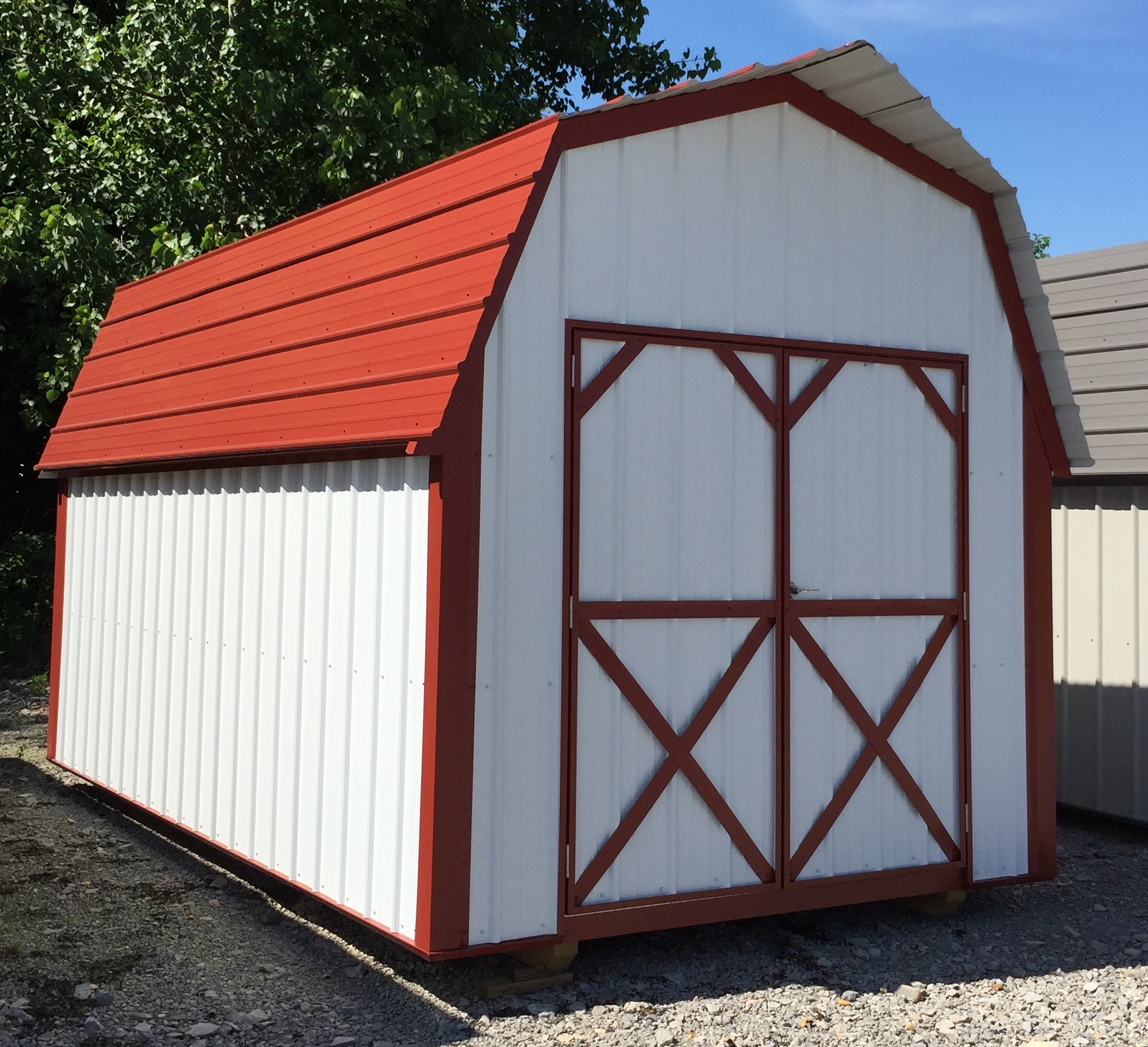White metal lofted barn with red trim and roof