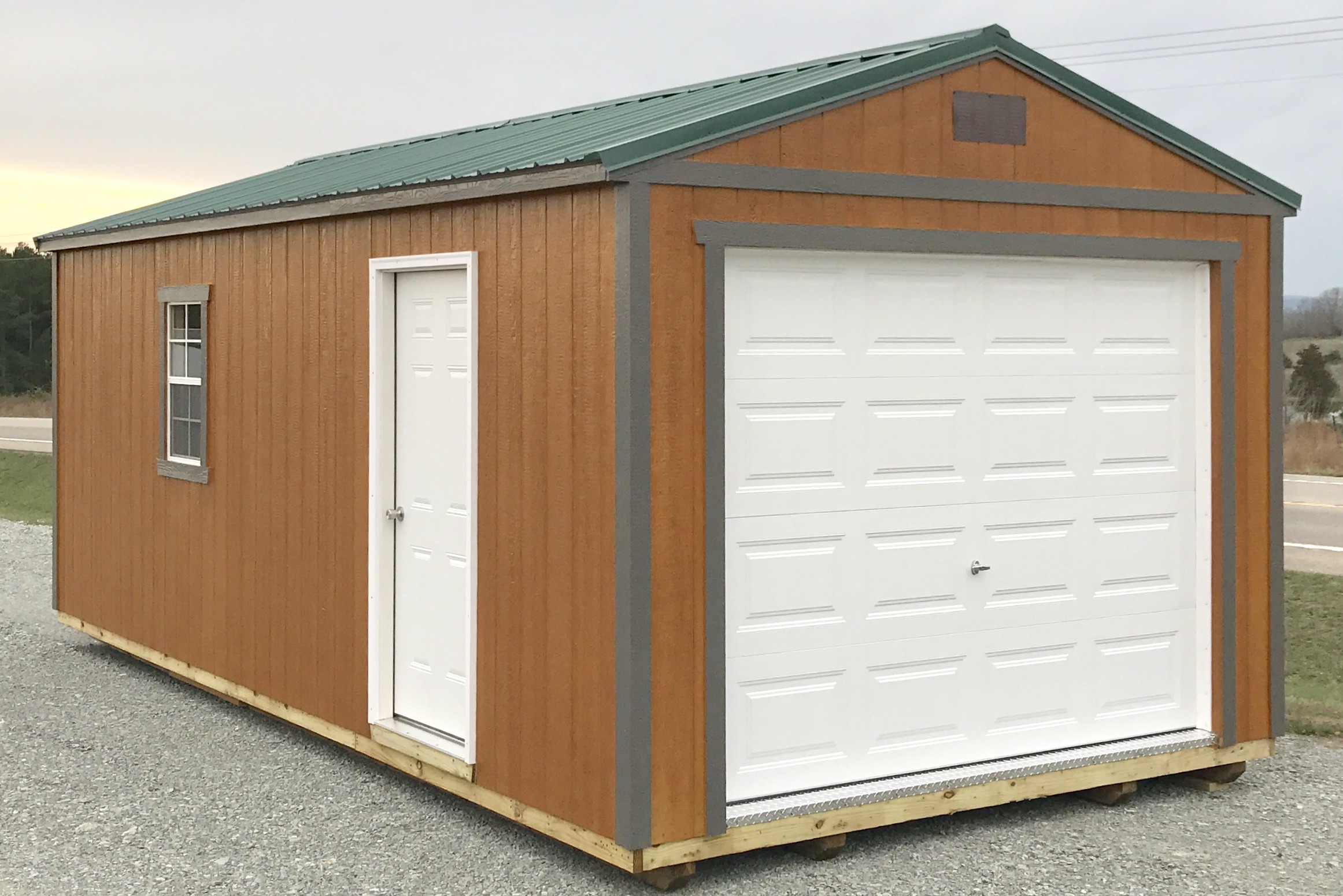 Brown urethane garage with gray trim, white doors, and green roof