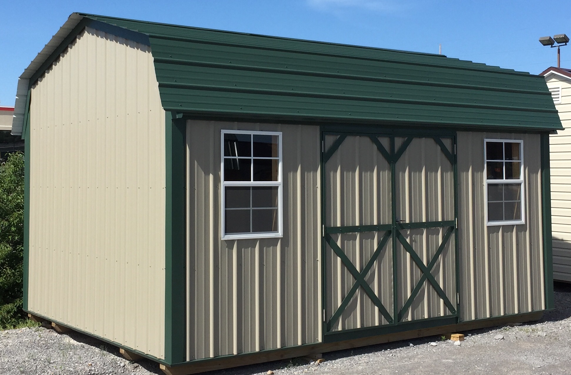 Tan metal side lofted barn with green trim and roof
